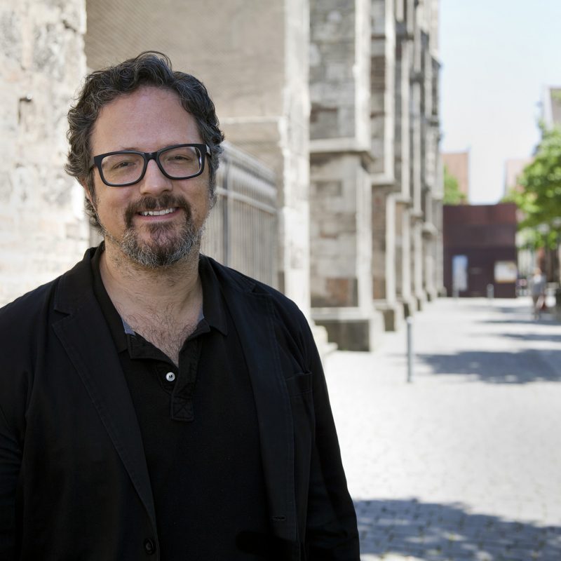 Artist Rafael Lozano-Hemmer standing in a bright sunny street