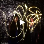 Two women make bright light patterns in the air using their gestures