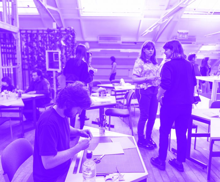 A group of young adult makers stand around chatting in a workshop on future high street